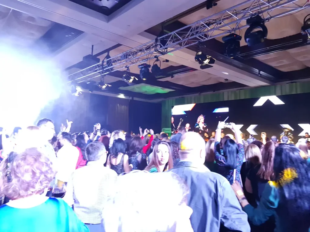 Public cu mâinile ridicate la un eveniment corporate cu ecran LED