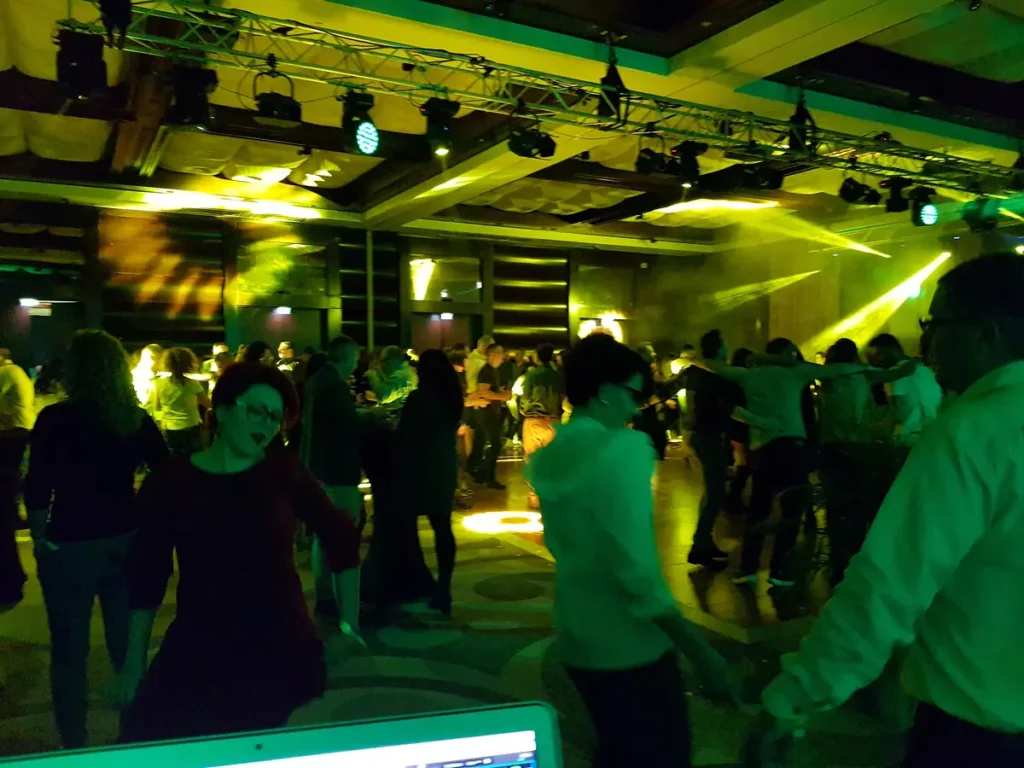 Invitați dansând sub lumini verzi, cu consola DJ în prim-plan