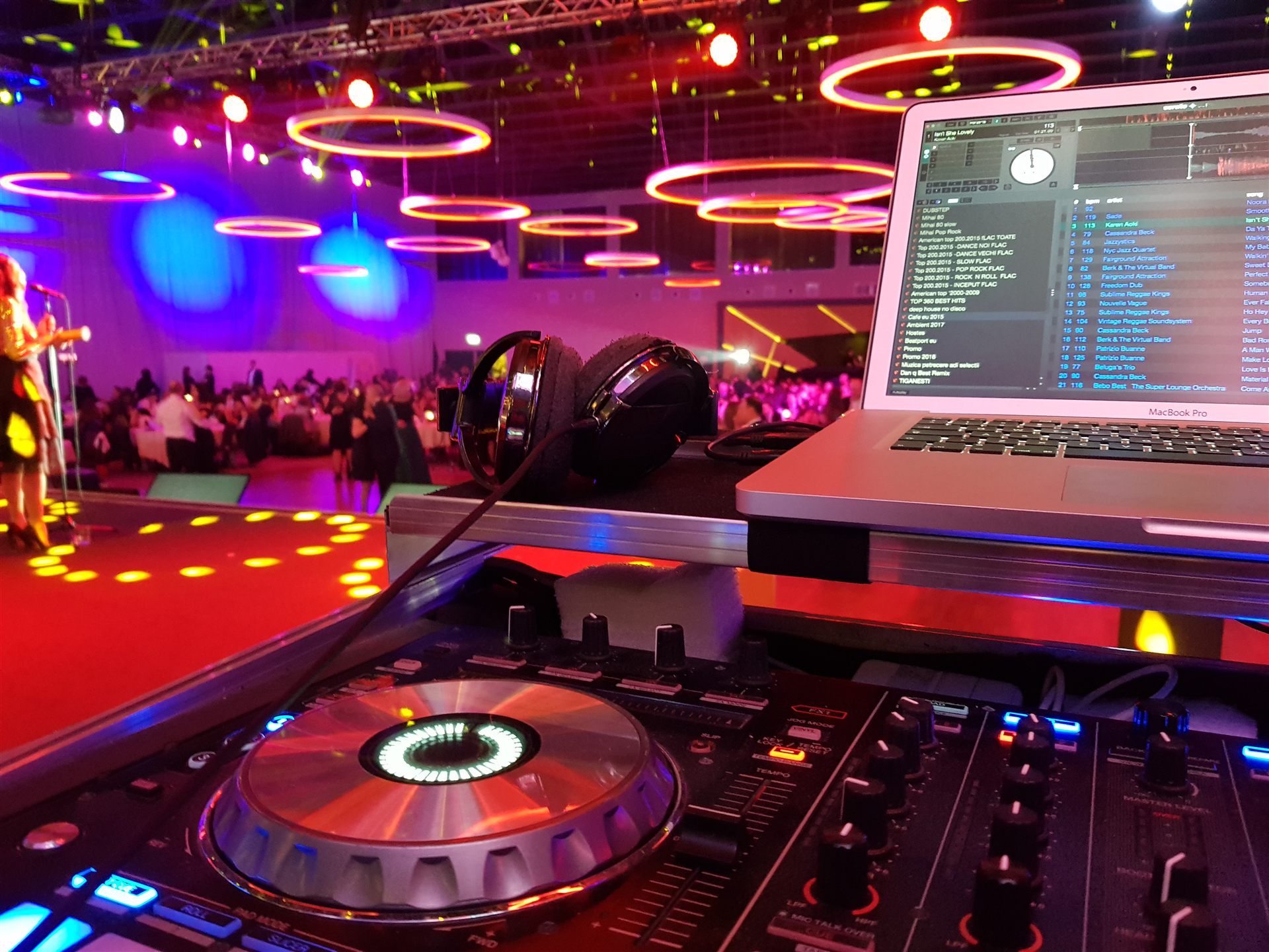 DJ pregătind muzica la consolă, cu petrecerea în fundal