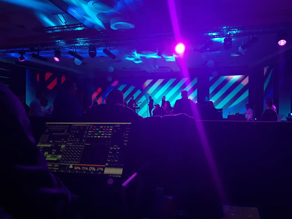 Public la un eveniment corporate, sub lumini albastre și violet