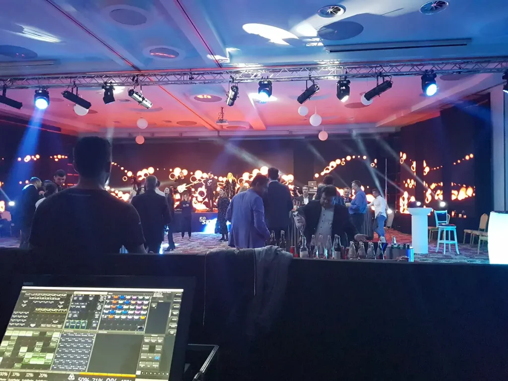 Scenă de eveniment corporate cu pupitru de control lumini și instalație LED